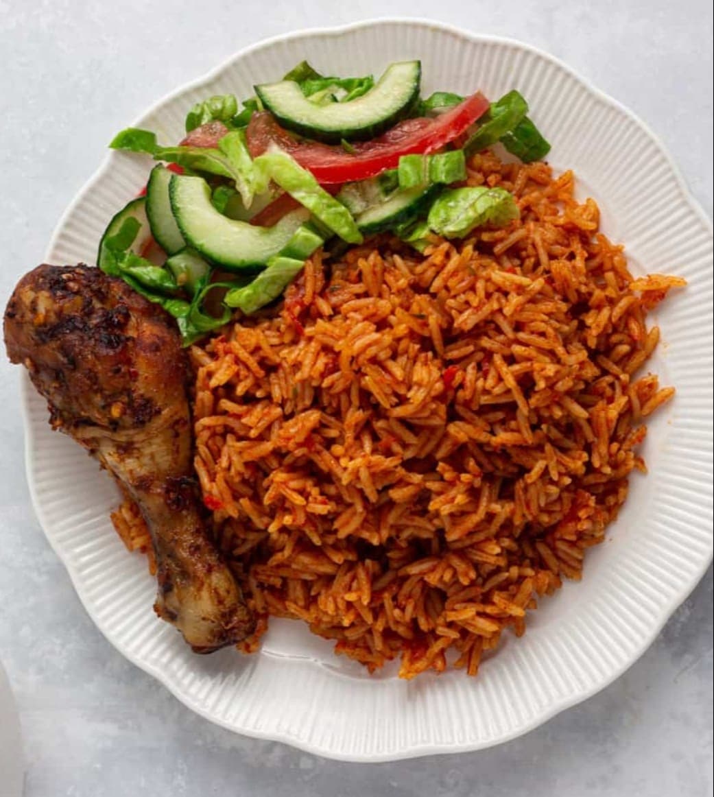 Jollof rice with baked chicken and fresh greens